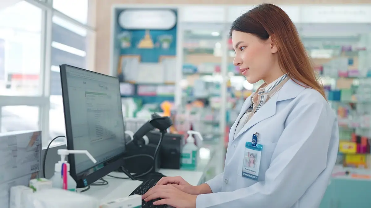 Pharmacist in a white coat checking an order on a computer