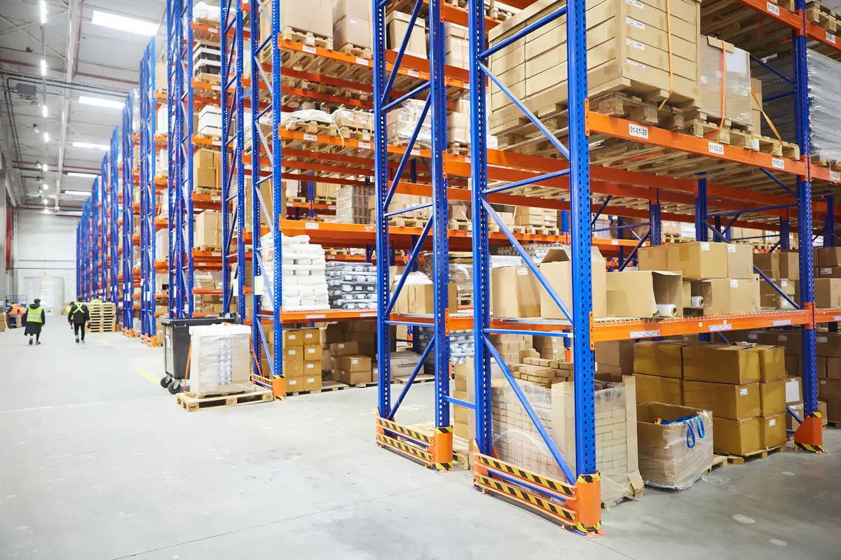 Aisle of a distribution warehouse with pallets of boxed goods on tall racking